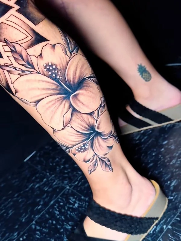 Hibiscus and florals on a calf, tattooed by Jordan
