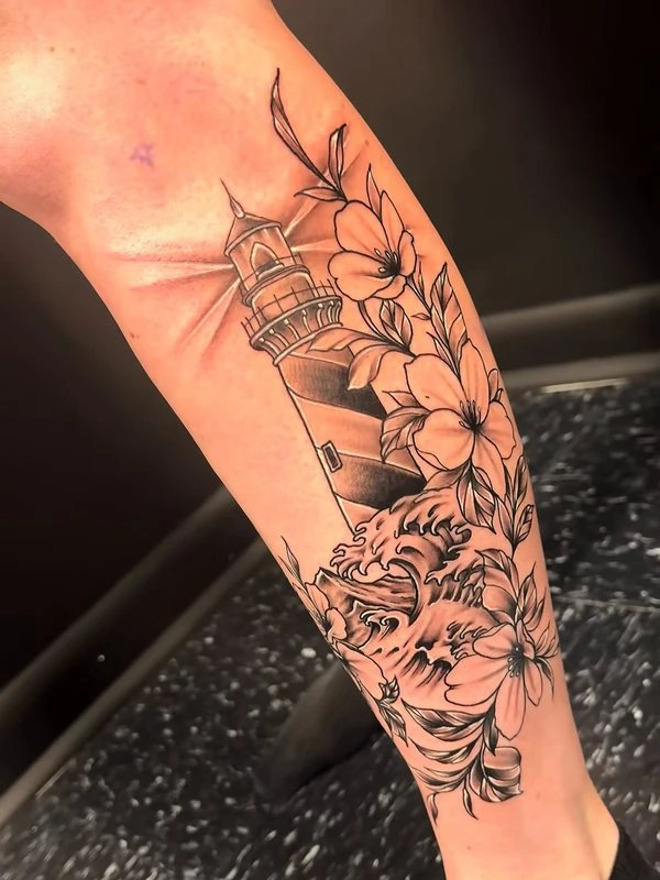 Lighthouse and florals on a calf, tattooed by Jordan